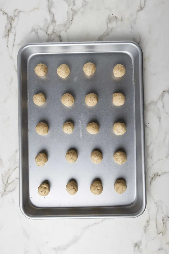 Shaping the Mexican tea cookies into balls and placing them on a cookie sheet.