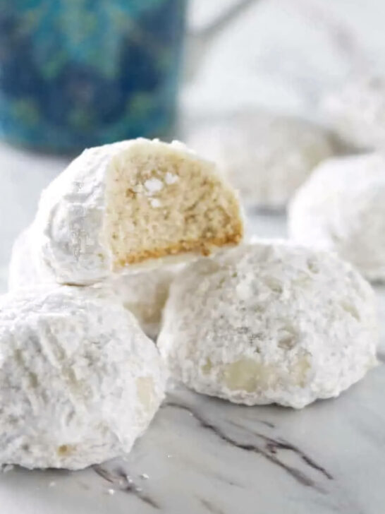 A partially eaten cookie on a stack of more snowball cookies.