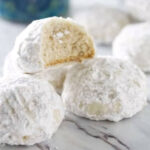 A stack of snowball cookies covered in powdered sugar.