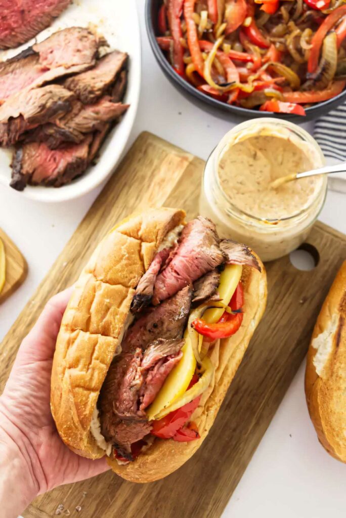 A hand holding a tri tip sandwich in a hoagie bun. 