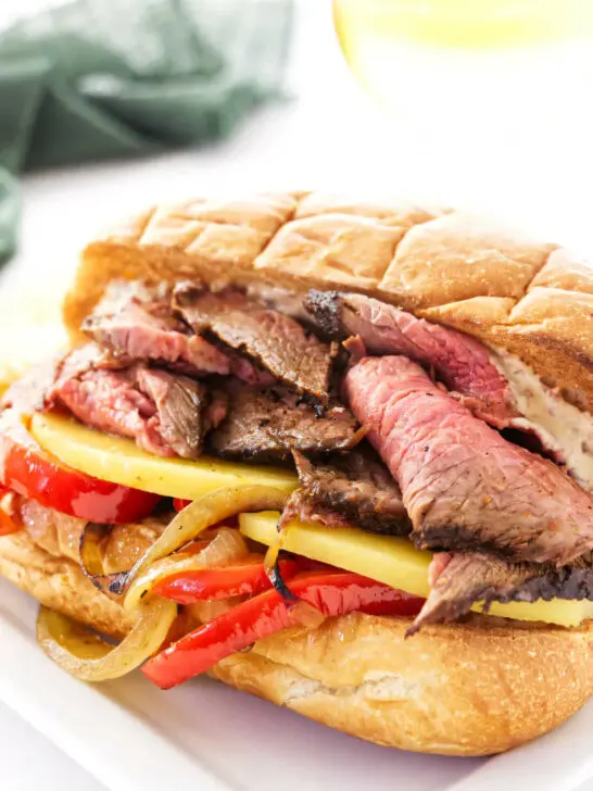 A sandwich with tri tip, cheese and sauteed onions and peppers.