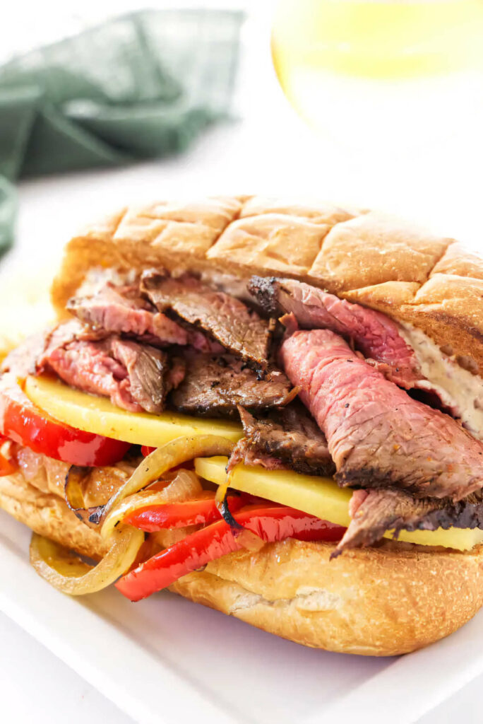 A sandwich with tri tip, cheese and sauteed onions and peppers.