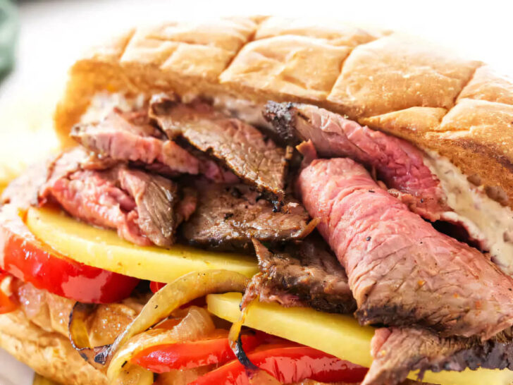 A sandwich with tri tip, cheese and sauteed onions and peppers.