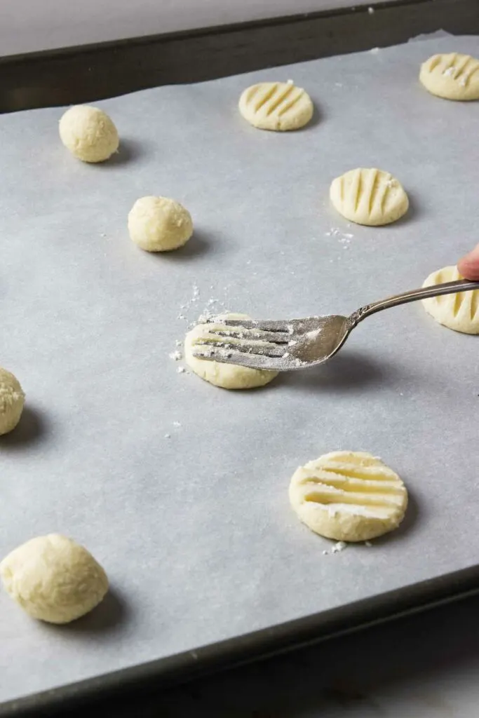 Making a recipe for shortbread cookies with cornstarch and flattening them with a fork.