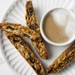 A plate filled with whole wheat biscotti and a cup of coffee.