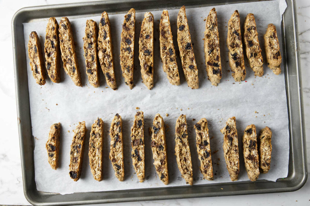 Several slices of biscotti on a baking sheet after being baked a second time.