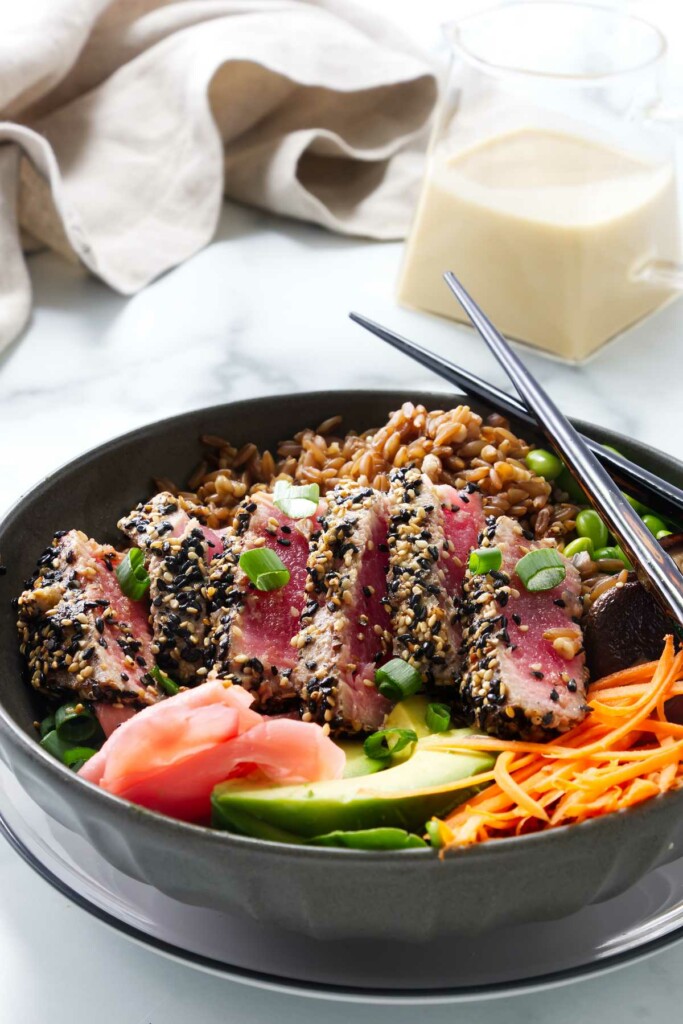 Seared tuna bowls with a jar of dressing in the background.