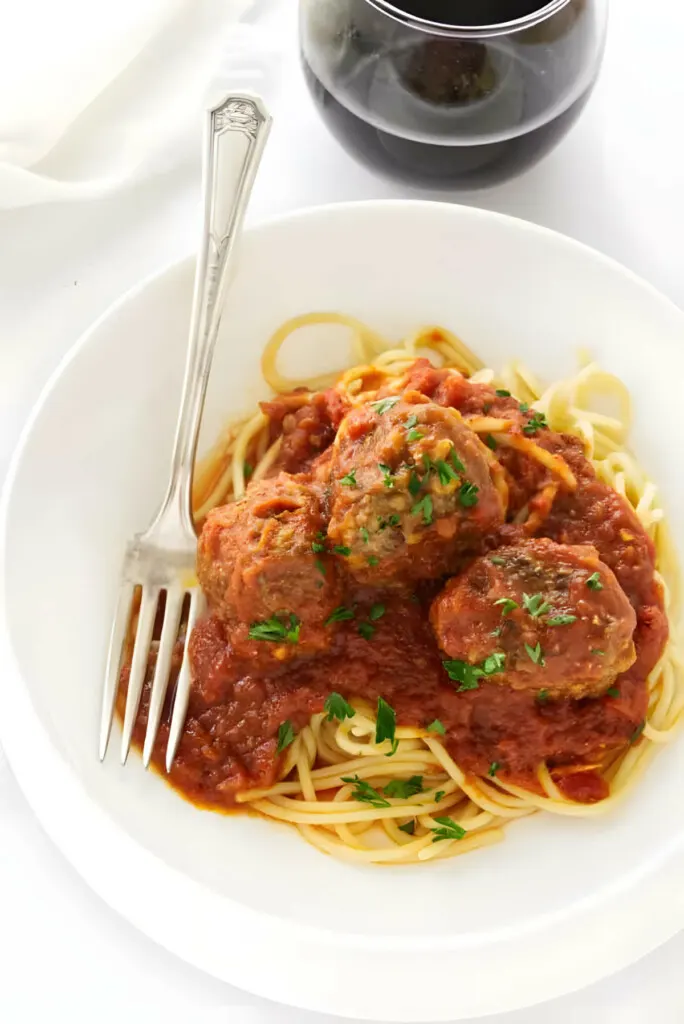 Meatballs and tomato sauce on a bed of spaghetti noodles.