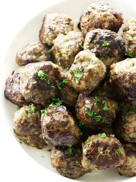 A bowl of stovetop meatballs with parsley garnish.