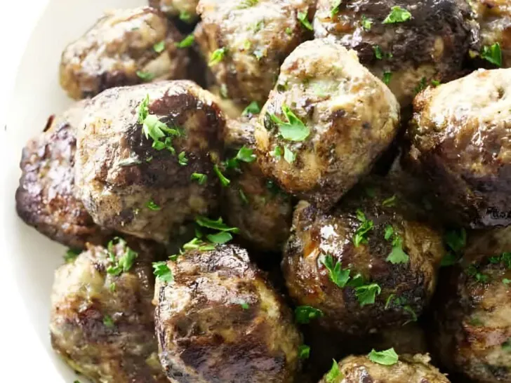 A bowl of stovetop meatballs with parsley garnish.