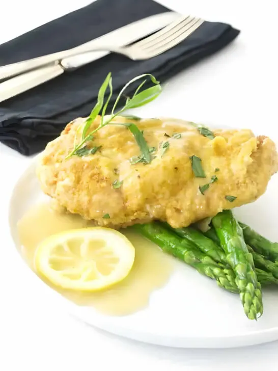 Chicken francese cutlet on a plate with asparagus.