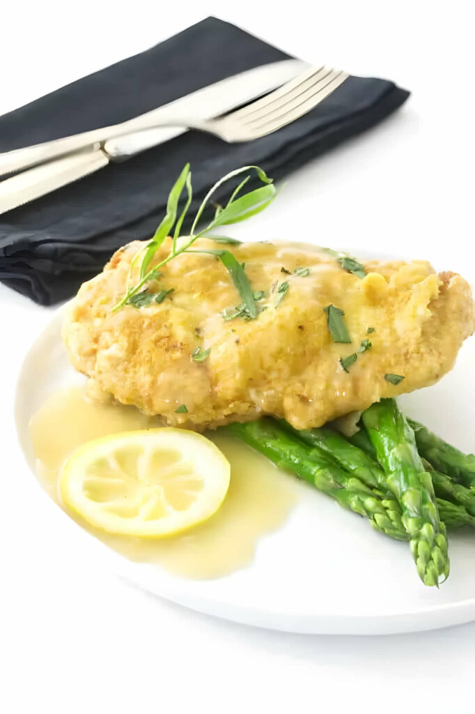 Chicken francese cutlet on a plate with asparagus.