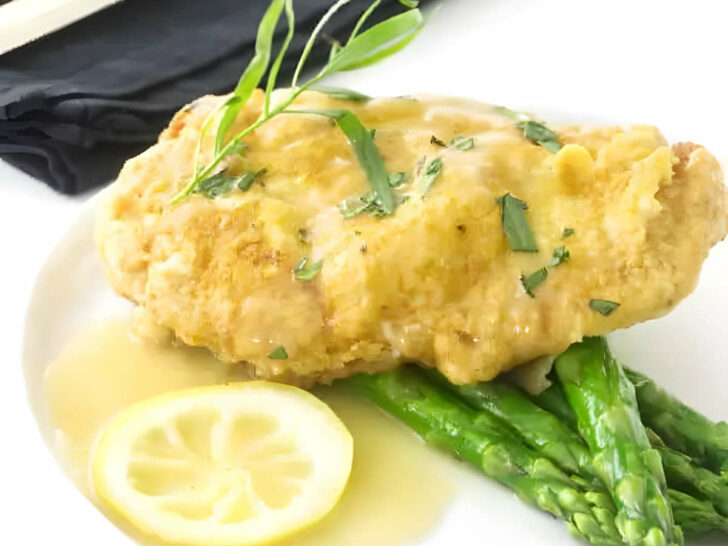 Chicken francese cutlet on a plate with asparagus.