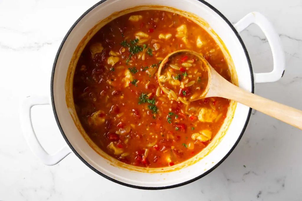 A ladle scooping some soup out of a pot.