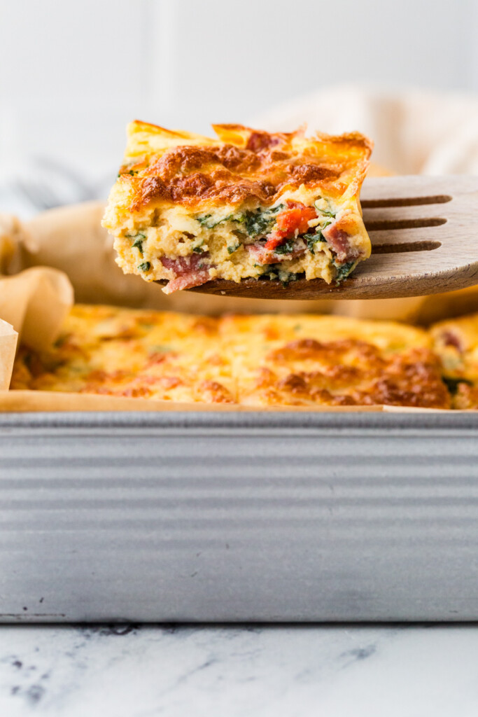 A spatula lifting up a slice of egg and cottage cheese casserole.