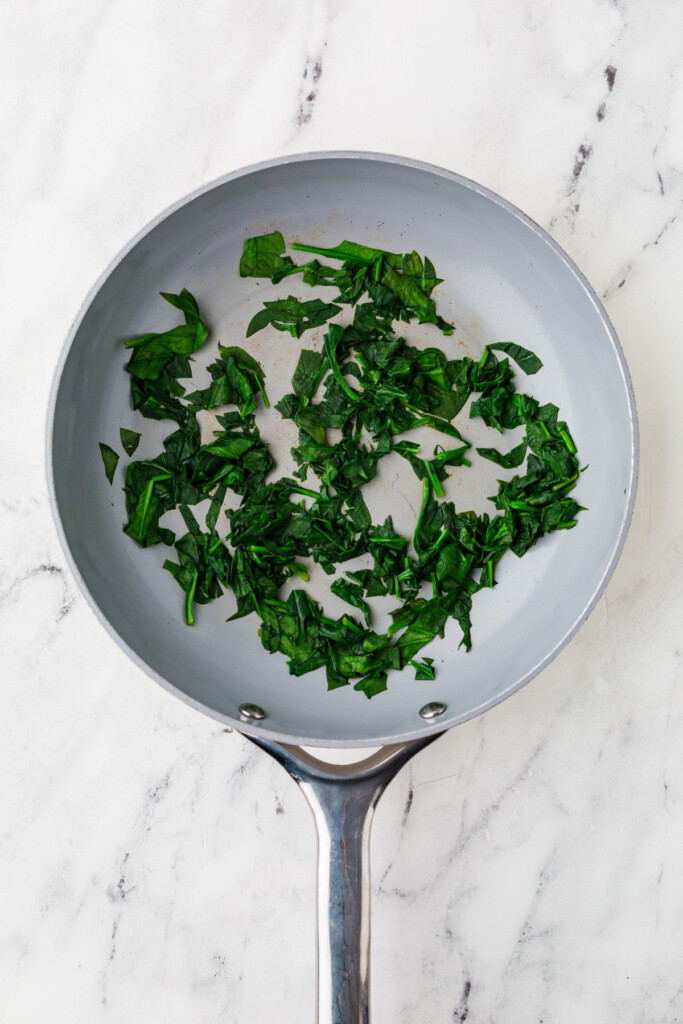 Cooking spinach in a skillet.