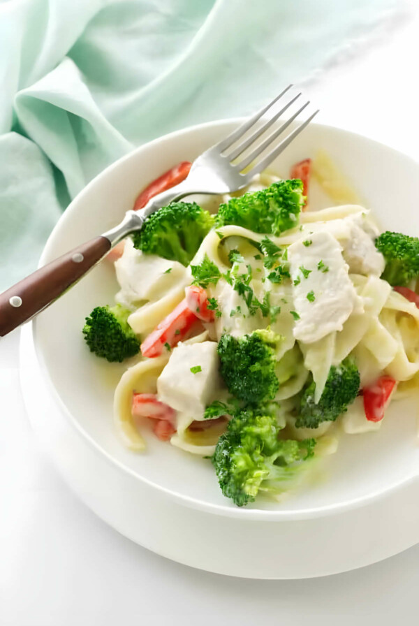 A bowl with chicken broccoli pasta in creamy sauce.