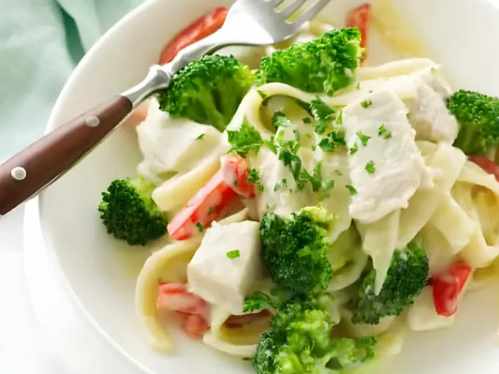 A bowl with chicken broccoli pasta in creamy sauce.