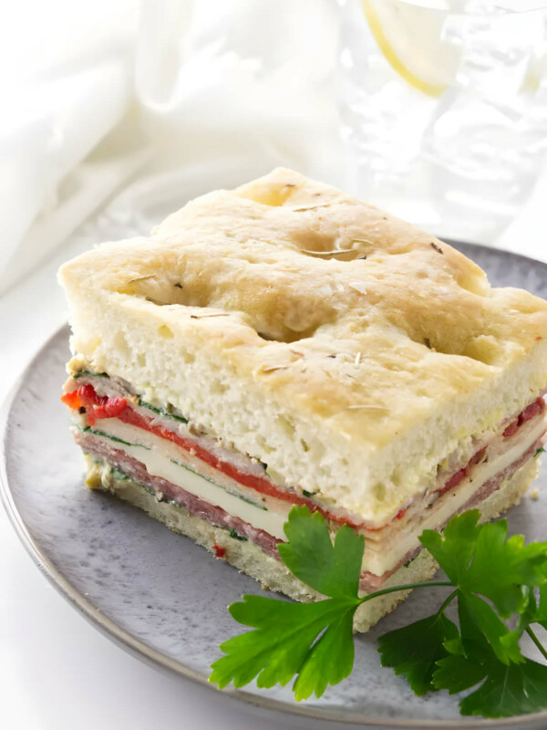 A slice of a sandwich made with focaccia bread, meats, and cheese.