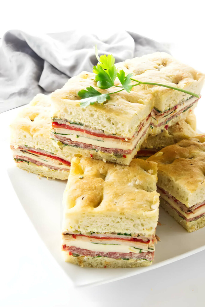 Several slices of a focaccia sandwich made with focaccia bread, meats, and cheese.