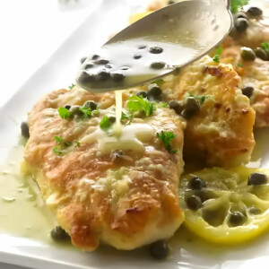 Drizzling lemon piccata sauce over pan fried chicken breast.