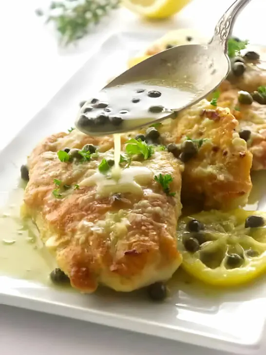 Drizzling lemon piccata sauce over pan fried chicken breast.