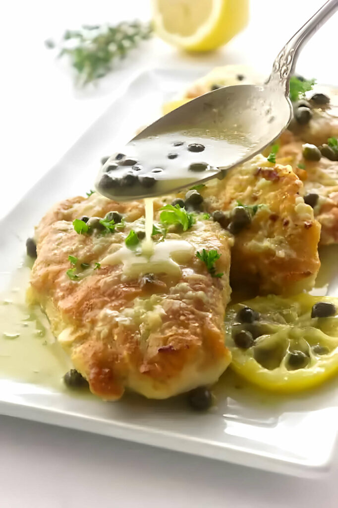 Drizzling lemon piccata sauce over pan fried chicken breast.