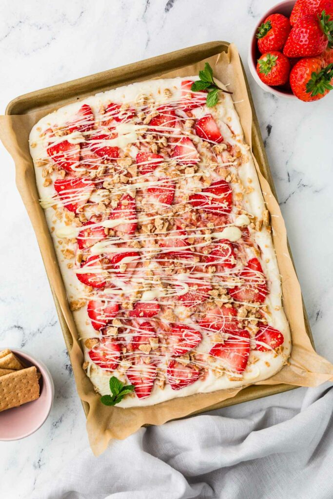 A slab of strawberry frozen yogurt bark on a sheet pan lined with parchment.