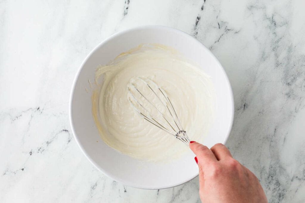 Blending yogurt with maple syrup and vanilla extract.