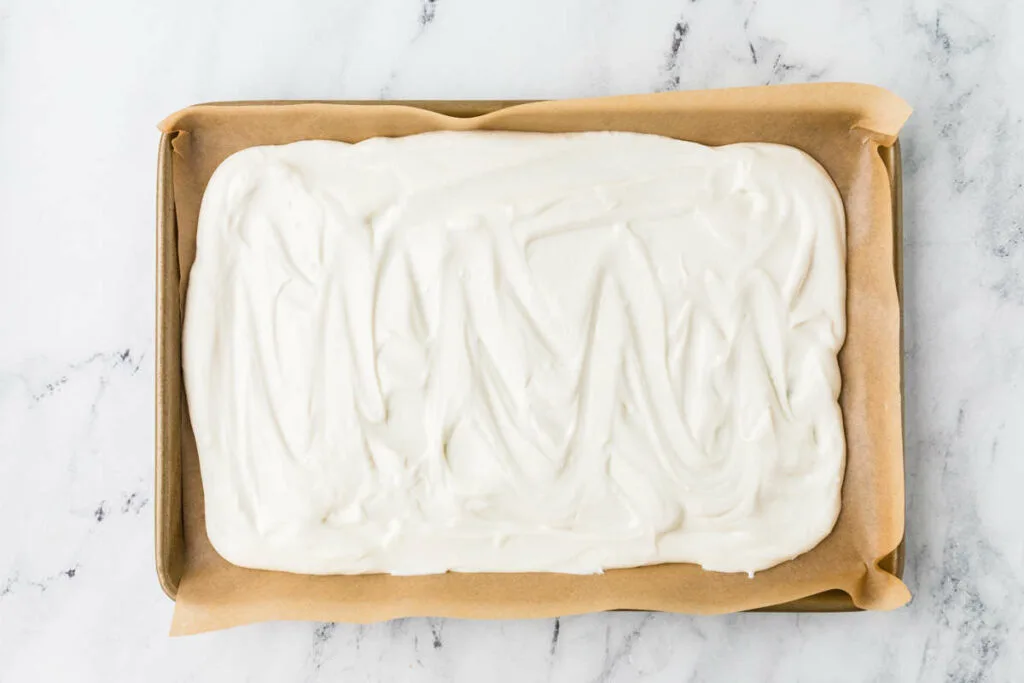 Spreading yogurt in a sheet pan lined with parchment.