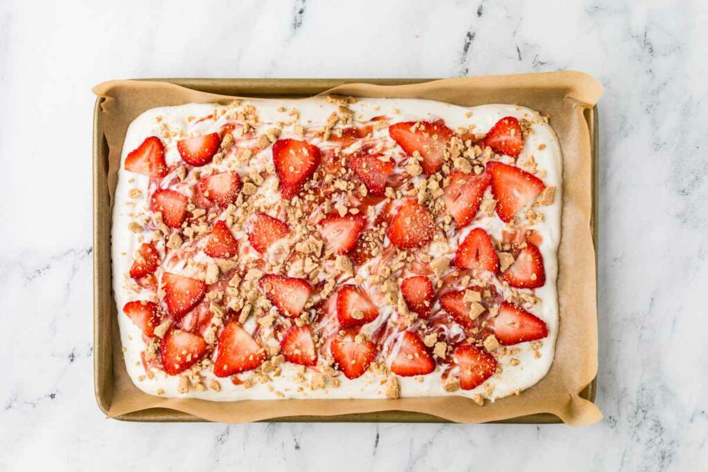 Sprinkling graham cracker crumbs on top of the yogurt bark.