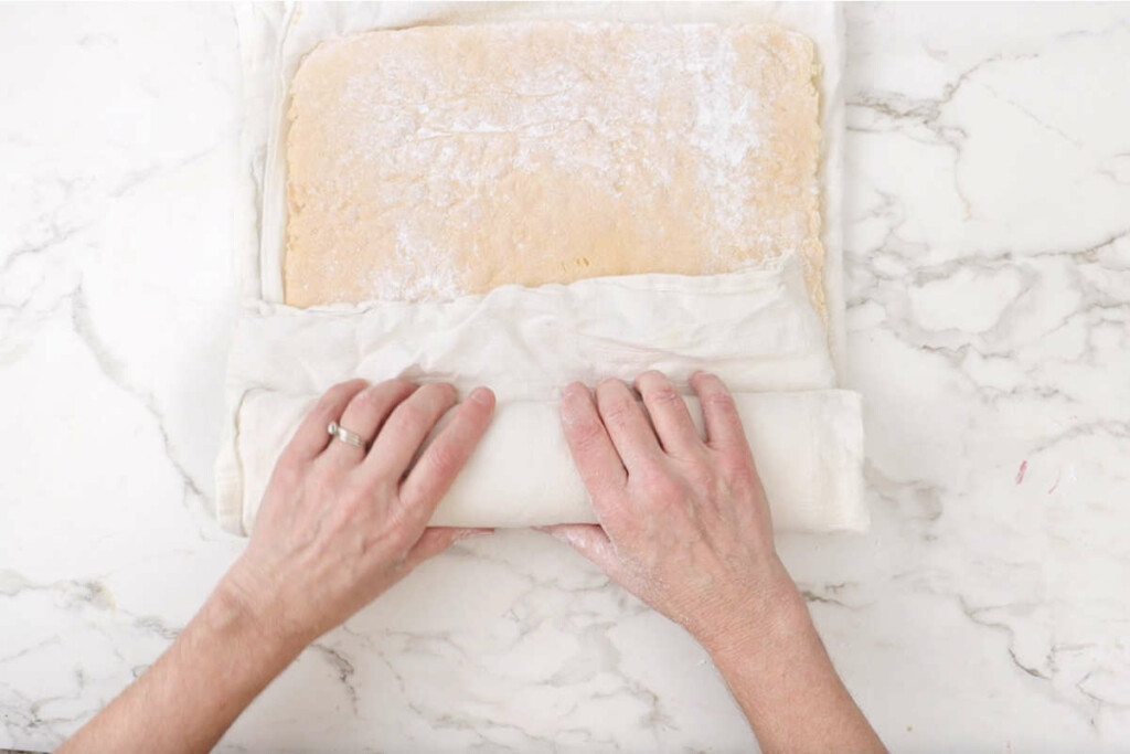 Rolling the sponge cake into a roll while it is still warm.