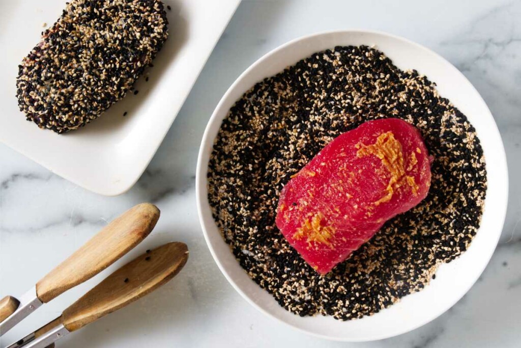 Coating tuna steaks in sesame seeds.