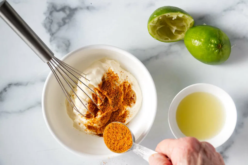 Combining spices and lime juice with mayonnaise to make a dressing.