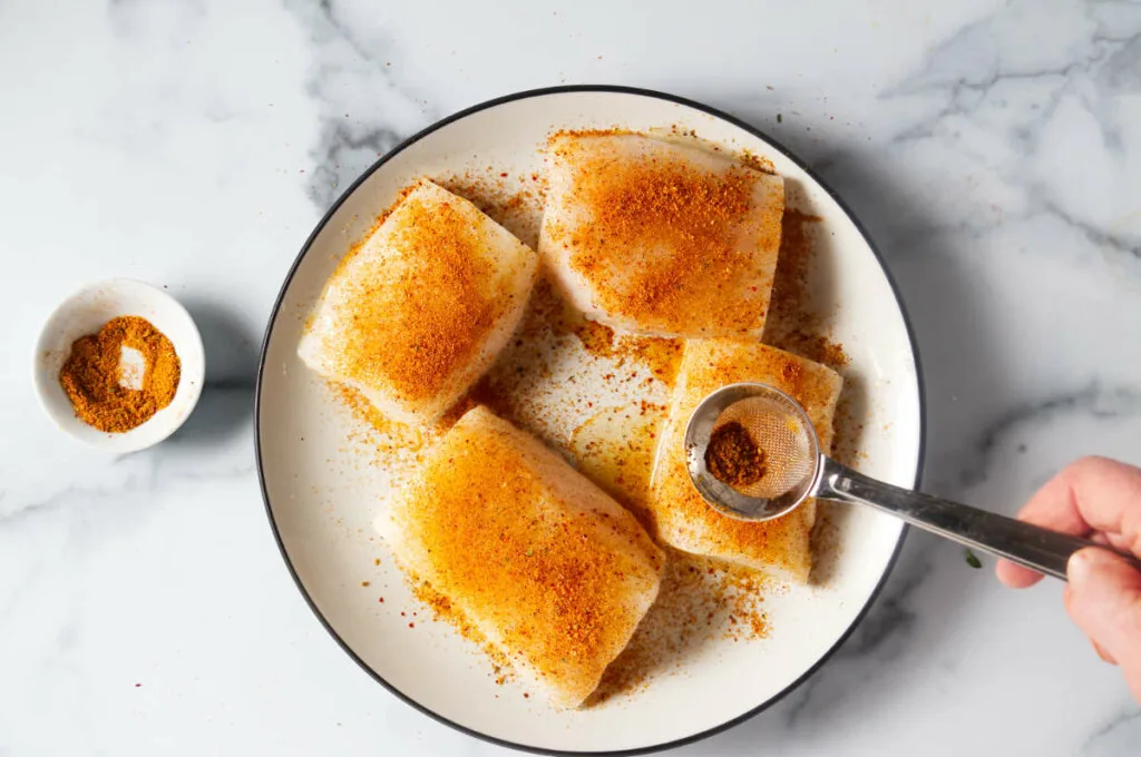 Seasoning the cod fillets.