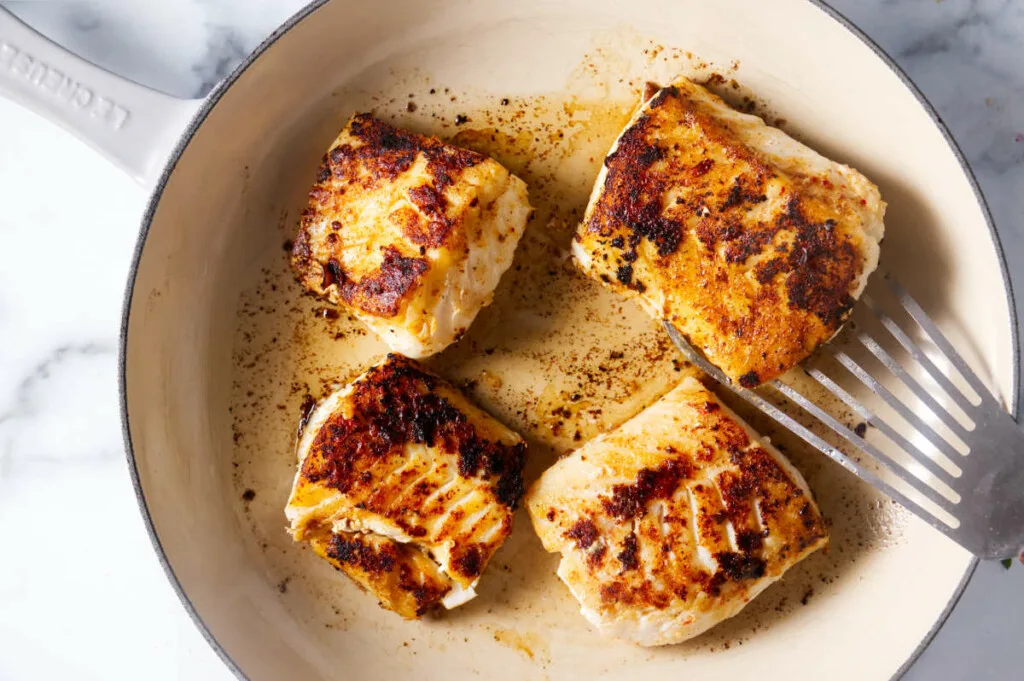 Searing cod fillets in a skillet.