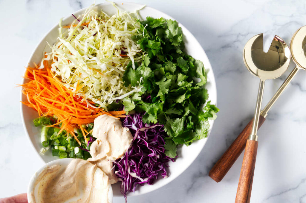 Pouring the dressing over the slaw for the tacos.