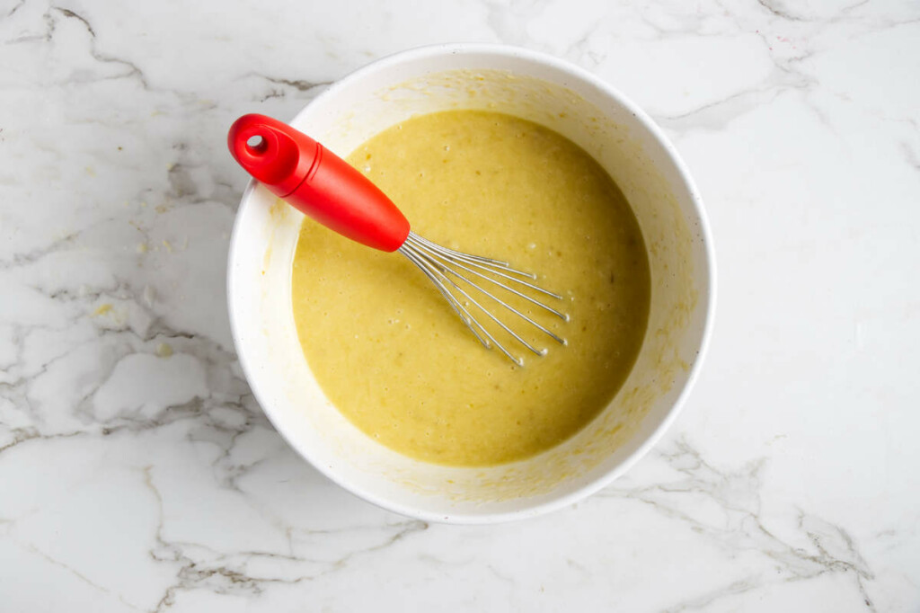 Mixing the wet ingredients into the bananas with a whisk.