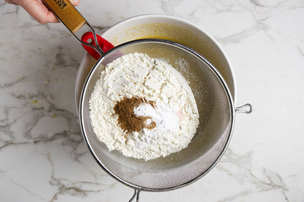 Sifting flour salt and nutmeg into the banana quick bread batter.