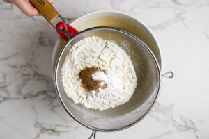 Sifting flour salt and nutmeg into the banana quick bread batter.