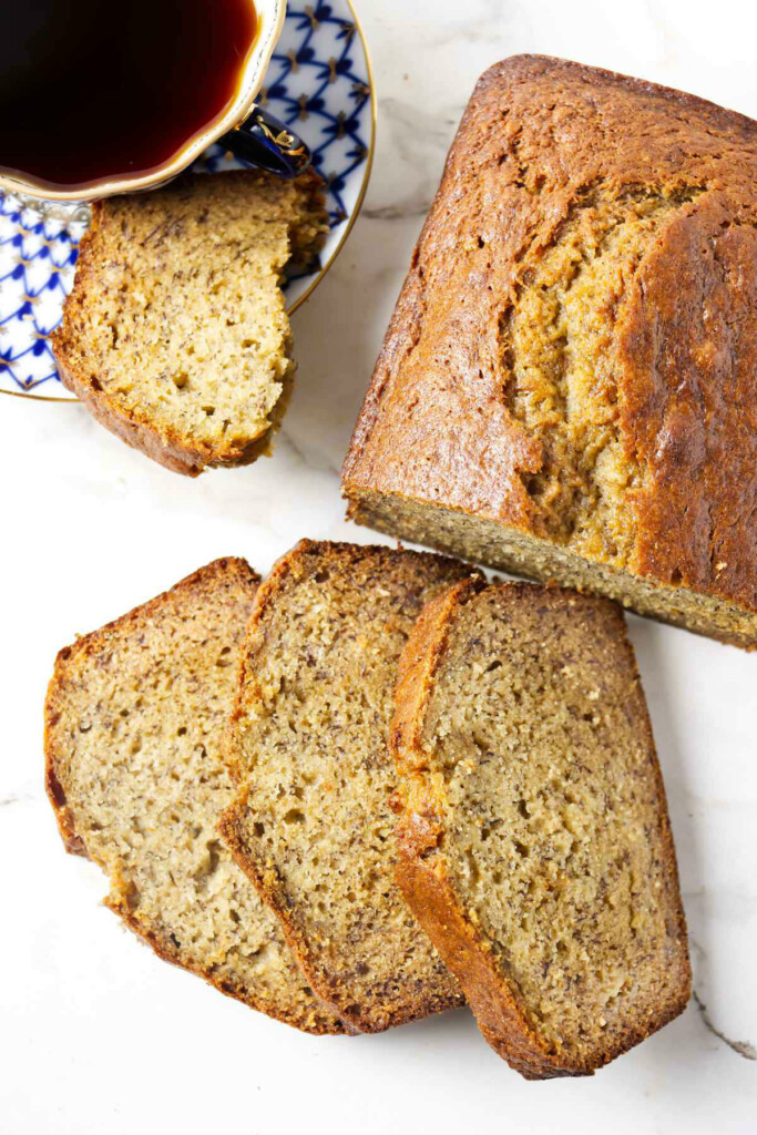 Several slices of banana bread next to a larger loaf.