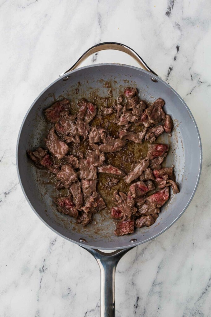 Searing the beef in a hot skillet.