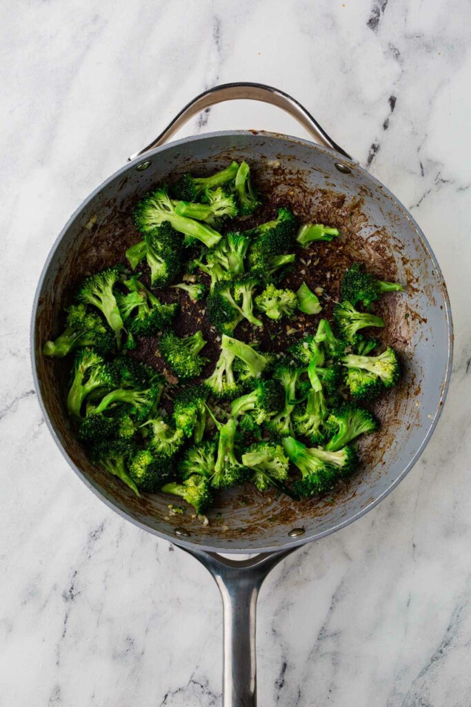 Stirring the broccoli into the pan.