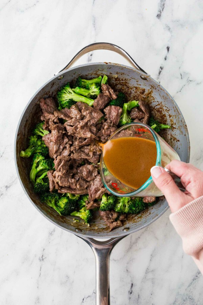 Adding the stir fry sauce to the skillet with the broccoli and beef.