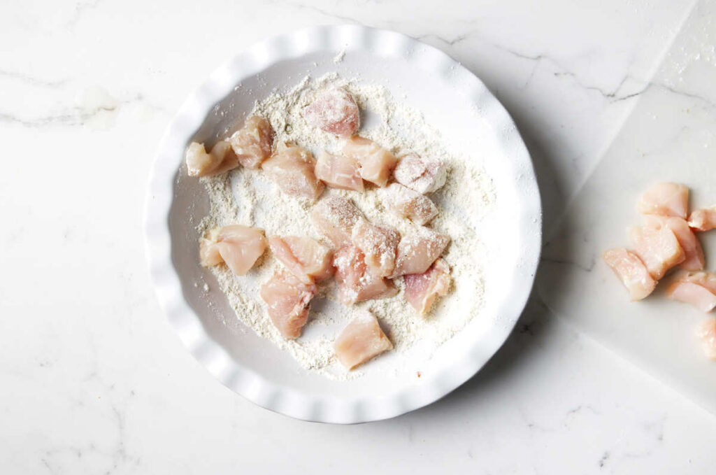 Coating the chicken with flour.