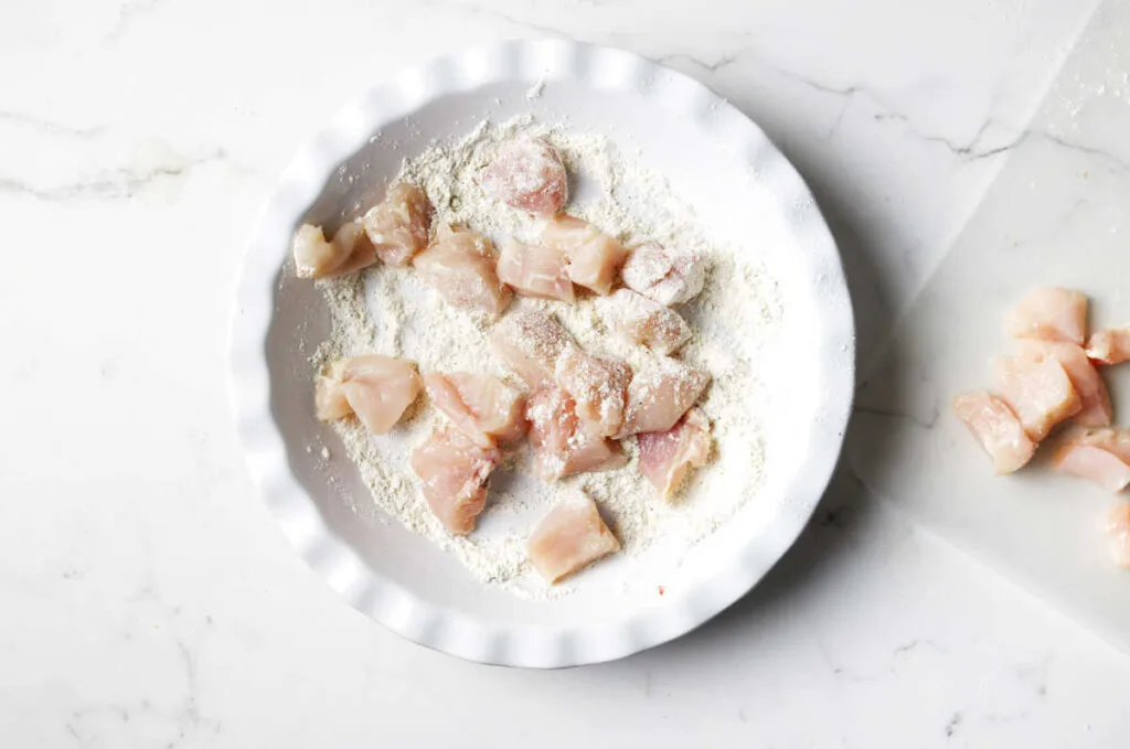 Coating the chicken with flour.