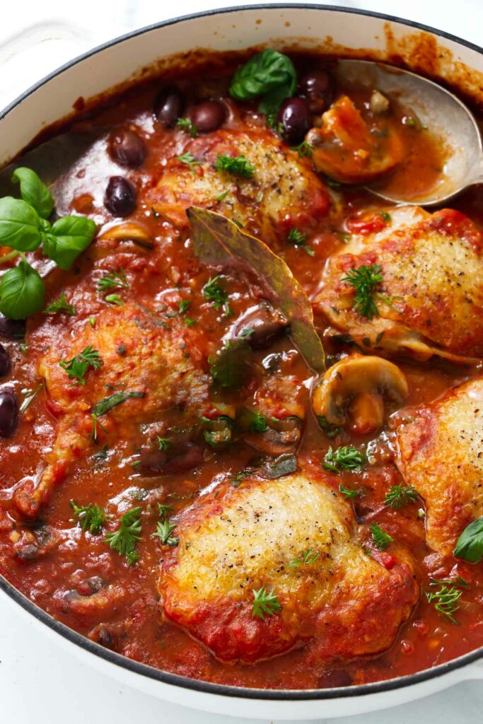 A one pot dish of chicken cacciatore with mushrooms in a large skillet.