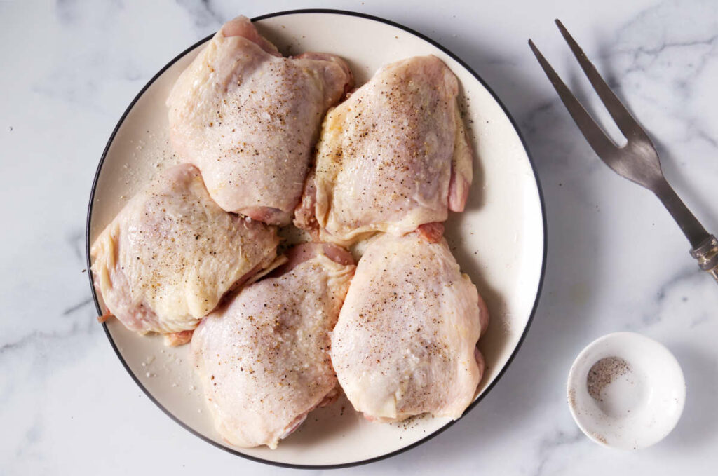 seasoning the chicken with salt and pepper.