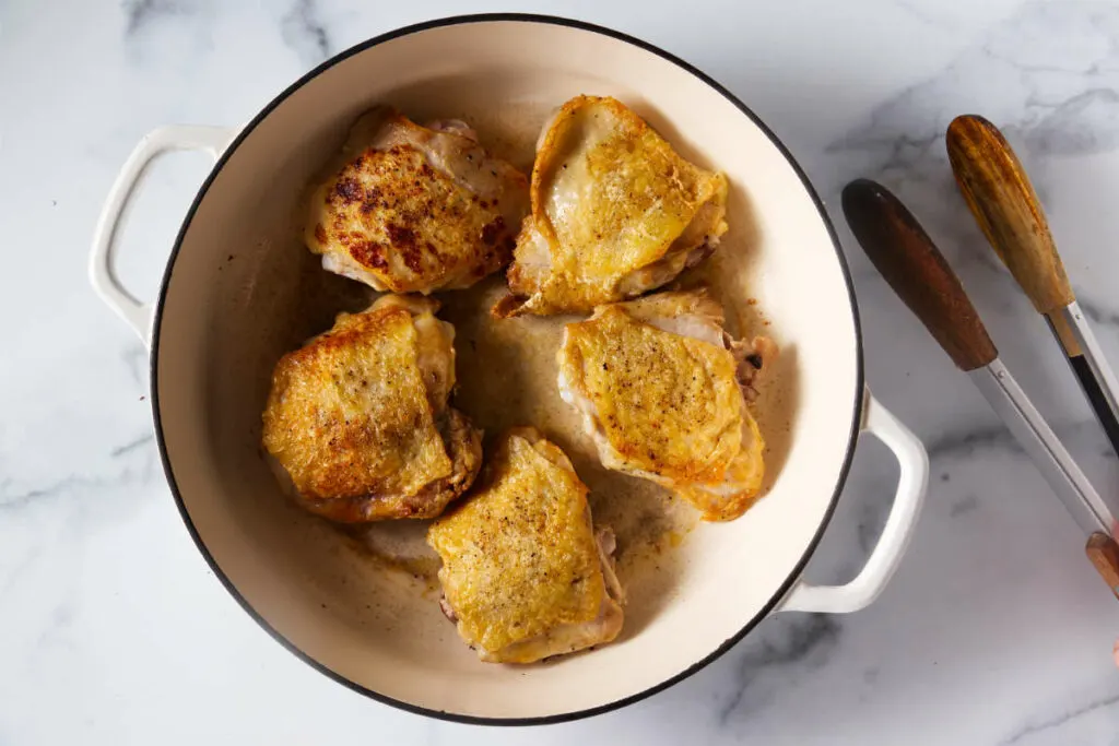 Browning chicken thighs in a skillet.