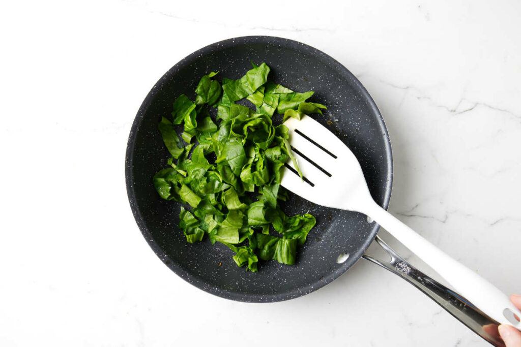 Cooking spinach in a skillet.